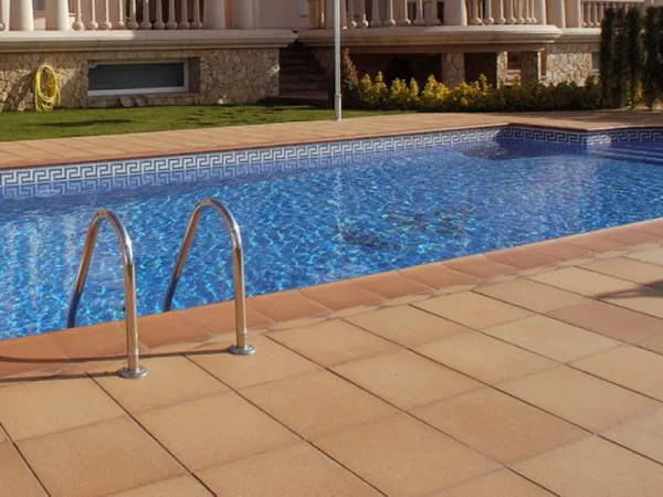 Piscina con azulejos efecto barro en tonos cálidos, colección Breda de Gres de Breda