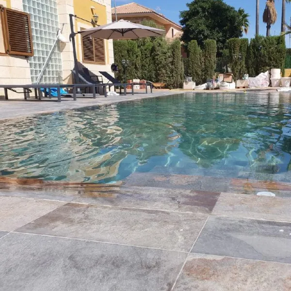 Piscina con azulejos efecto piedra en tonos fríos, colección Aspen de Mikonos