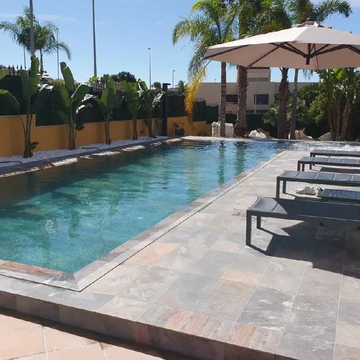 Piscina con azulejos efecto piedra en tonos fríos, colección Aspen de Mikonos