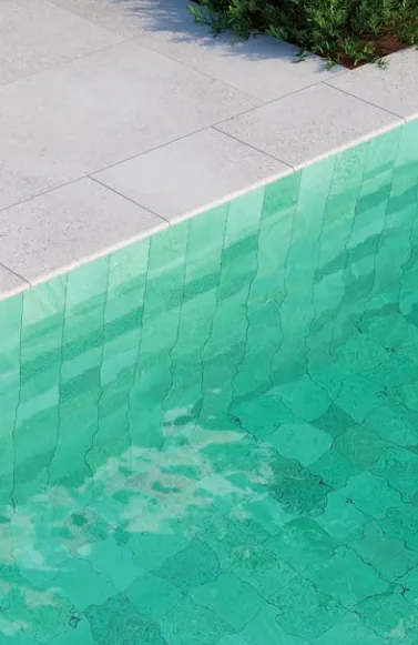 Piscina con azulejos efecto piedra en tonos fríos, colección Bali de Mayor