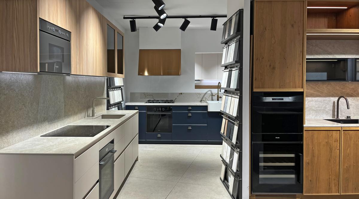 Cocina con encimera clara, columna de hornos y mobiliario de madera en la exposición de Ferrolan